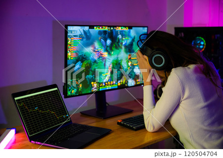 Game over you lose. Angry Asian gamer with gaming headphones playing video game on computer PC at home feeling sad disappointed about NFT game losing graph investors sulk down, player unhappy 120504704