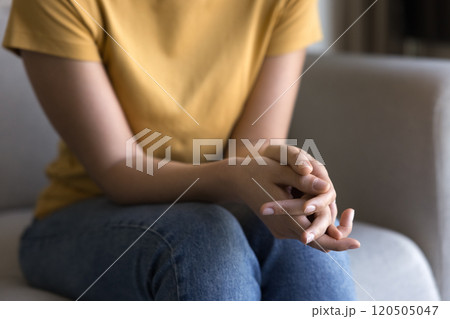 Young woman holding folded hands on lap Young woman holding folded hands on lap 120505047