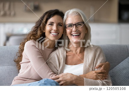 Portrait of two different generations women hugging sitting on sofa Portrait of two different generations women hugging sitting on sofa 120505108