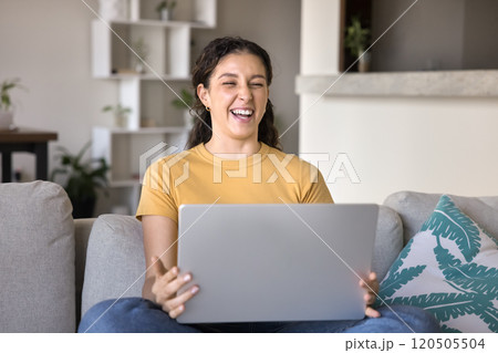 Happy joyful young 20s Latin woman using laptop at home Happy joyful young 20s Latin woman using laptop at home 120505504