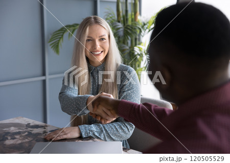 Positive successful young blonde business woman giving handshake to coworker 120505529