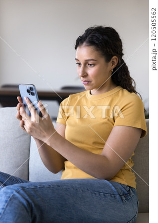 Beautiful young 20s Latin woman using home application on smartphone 120505562