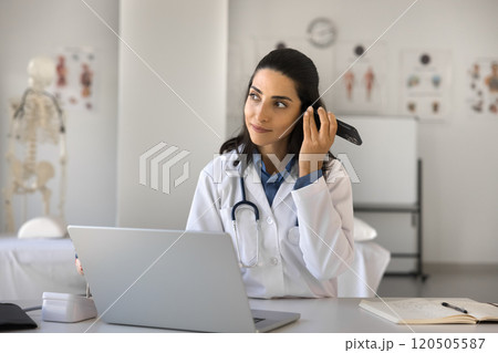 Cardiologist holds smartphone near ear listening voice mail from patient 120505587