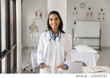 Portrait of young Latina female doctor standing in examination room 120505591