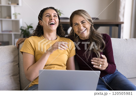 Senior Hispanic mother and young daughter woman laughing at laptop Senior Hispanic mother and young daughter woman laughing at laptop 120505981
