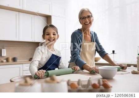 Granny her granddaughter wear aprons cooking, posing for camera Granny her granddaughter wear aprons cooking, posing for camera 120506361