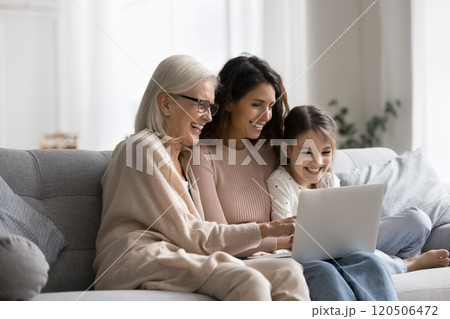 Multigenerational family resting on sofa with laptop laughing, watching movie 120506472