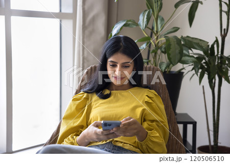 Positive attractive Indian woman typing text message on mobile phone Positive attractive Indian woman typing text message on mobile phone 120506510