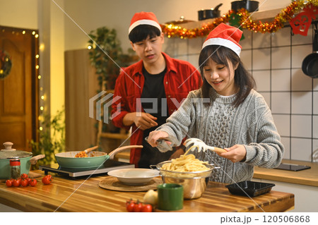 Beautiful young couple enjoying dinner preparations in kitchen on Christmas eve 120506868