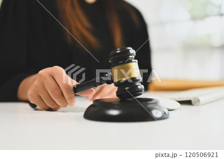 Female judge in black robe holding a gavel poised above sound block symbolizing legal authority and justice Female judge in black robe holding a gavel poised above sound block symbolizing legal authority and justice 120506921
