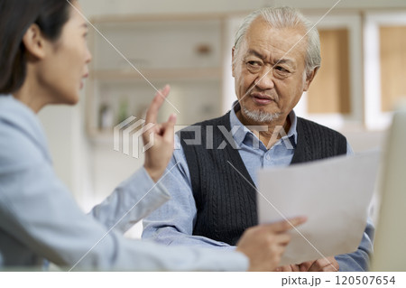 asian old man appears to be unconvinced while listening to a salesperson asian old man appears to be unconvinced while listening to a salesperson 120507654