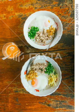 Hot Chinese congee (rice porridge) with minced pork on wooden table 120507760