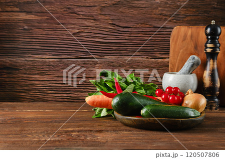 Fresh vegetables arranged on a wooden table with rustic backdrop in a cozy kitchen setting 120507806