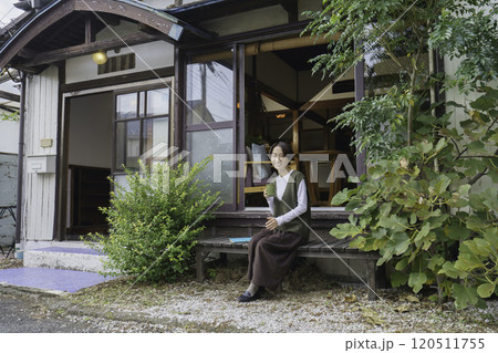 古民家の縁側に座って飲み物を飲むミドルエイジの女性 120511755
