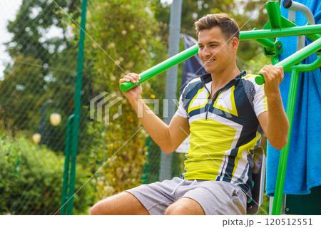 Man flexing arm in outdoor gym 120512551