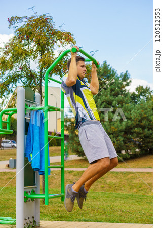 Man doing pull ups in outdoor gym 120512553