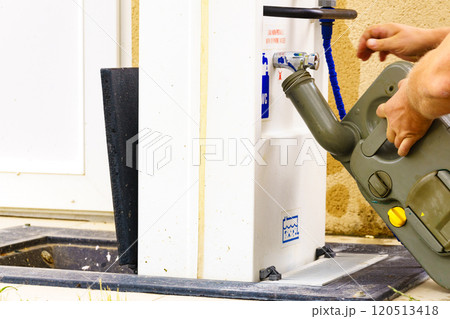 Man emptying caravan tank toilet cassette in dump station. 120513418