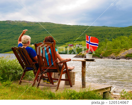 Couple relaxing on norwegian fjord shore 120514067