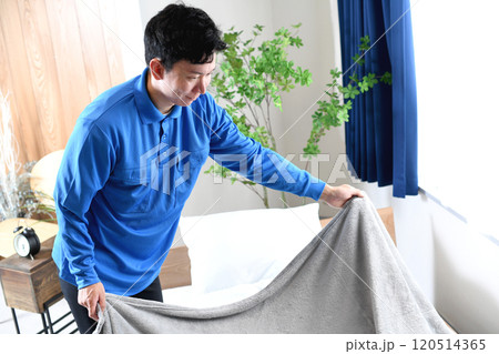 ベッドメイキングする作業着のアジア人男性 120514365