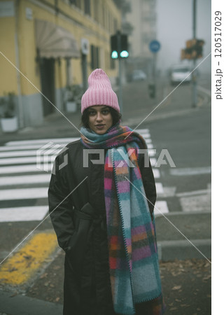 A woman in a pink hat and scarf stands on a crosswalk A woman in a pink hat and scarf stands on a crosswalk 120517029
