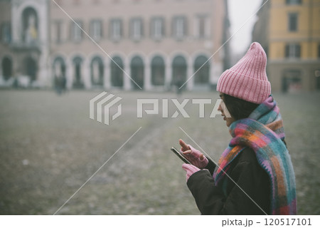 A woman in a pink hat and scarf is looking at her cell phone 120517101