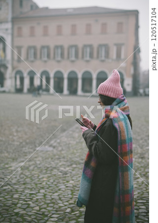 A woman in a pink hat and scarf stands in front of a building 120517104