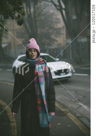 A woman in a pink hat and scarf stands on the roadside A woman in a pink hat and scarf stands on the roadside 120517109