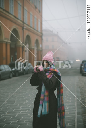 A woman is capturing a picture of herself on a foggy street today 120517111