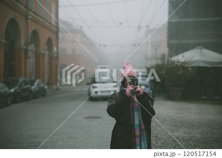 A woman is capturing a picture of a city street enveloped in fog, 120517154
