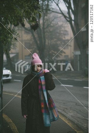 A woman in a pink hat and scarf stands by the roadside 120517162