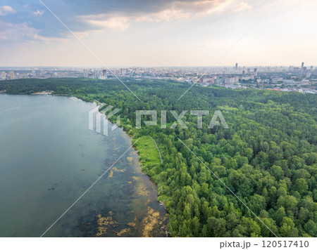 Big lake with green shores in bright sun light and city on horizon, aerial landscape. Recreation concept. Aerial view 120517410