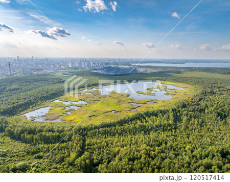 Big lake with green shores in bright sun light and city on horizon, aerial landscape. Recreation concept. Aerial view Big lake with green shores in bright sun light and city on horizon, aerial landscape. Recreation concept. Aerial view 120517414