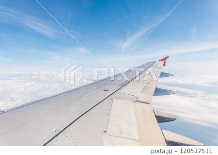View from the airplane window at a beautiful cloudy sky and the airplane wing View from the airplane window at a beautiful cloudy sky and the airplane wing 120517511
