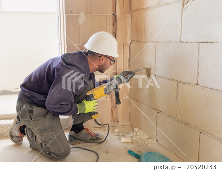 Craftman drilling a hole with a pneumatic hammer drill perforator in a brick wall 120520233