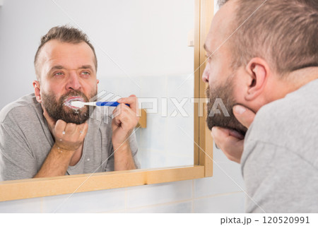 Bored guy brushing his teeth in bathroom 120520991