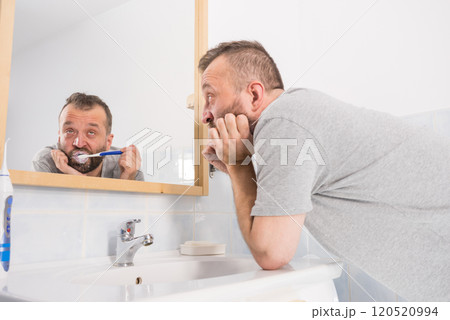Bored guy brushing his teeth in bathroom 120520994