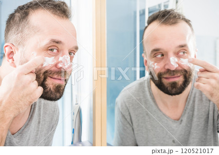 Man applying moisturizer cream in bathroom 120521017