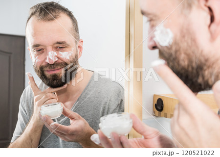 Man applying moisturizer cream in bathroom 120521022