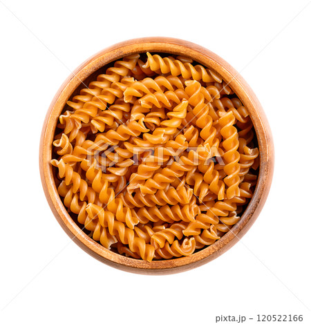 Chickpea spiral pasta, gluten free noodles in a wooden bowl, isolated from above. Small fusilli, a pasta variety with helical or corkscrew shape, made of chickpea flour, an alternative to wheat flour. 120522166