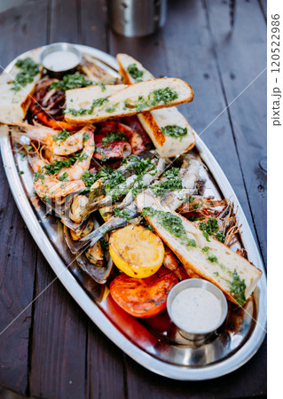 Gourmet seafood platter with grilled shrimp, mussels, fish, and herb topped bread on silver tray. Gourmet seafood platter with grilled shrimp, mussels, fish, and herb topped bread on silver tray. 120522986