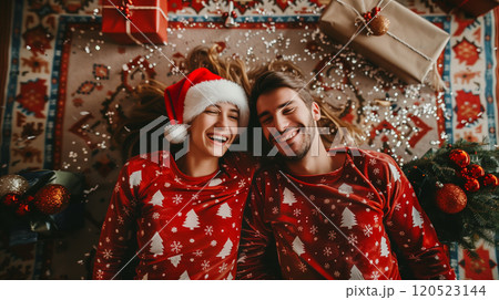 Laughing Couple On Their Backs Wearing Matching Holiday Pajamas Surrounded By Christmas Gifts. Generative AI. 120523144