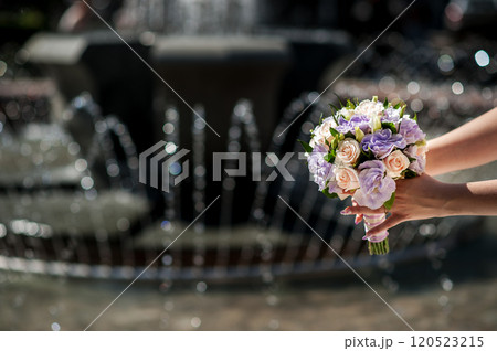 Hand of bride holding wedding bouquet on a fountain Hand of bride holding wedding bouquet on a fountain 120523215