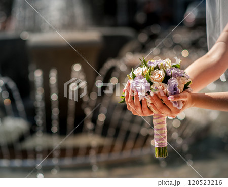 Hand of bride holding wedding bouquet on a fountain Hand of bride holding wedding bouquet on a fountain 120523216