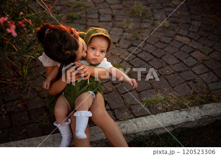 upper view of of two sitting children, bigger one holding smaller one in hands 120523306