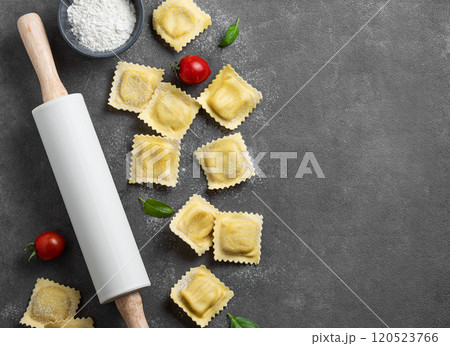 Flat lay of pasta ravioli with tomato and basil on dark background with flour and rolling pin. Flat lay of pasta ravioli with tomato and basil on dark background with flour and rolling pin. 120523766