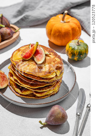 Stack of pumpkin pancakes with honey and figs on light background with fresh fruits and vegetables. Stack of pumpkin pancakes with honey and figs on light background with fresh fruits and vegetables. 120523778
