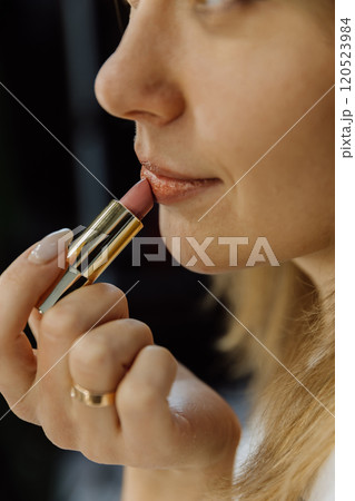 Close up of a woman applying nude lipstick for a natural and elegant makeup look 120523984