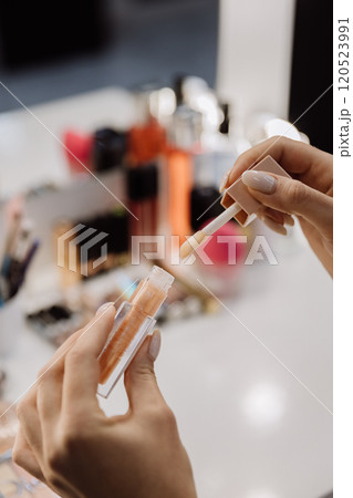Applying lip gloss with a sleek applicator for a perfect glossy finish 120523991