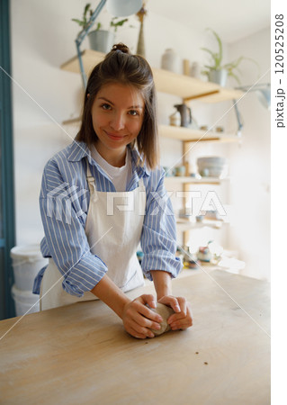 A Creative Woman Diligently Shaping Clay in a Bright and Inviting Studio Environment 120525208