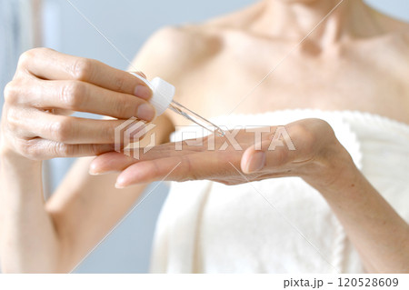 美容液を手に垂らす中年女性の手元 美容液を手に垂らす中年女性の手元 120528609